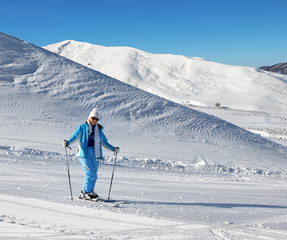 Fototapeta na wymiar Skier on snowy sunlight ski slope at nice sunny day
