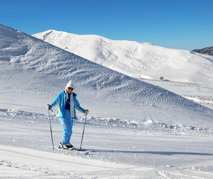 Skier on snowy sunlight ski slope at nice sunny day