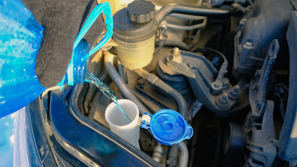 Pouring washer fluid into the car