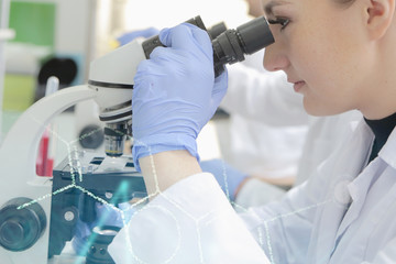 Young female scientist looking through a microscope in a laborat