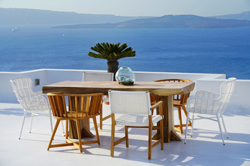 Beautiful location with wooden table and chairs overlooking the Caldera in Santorini