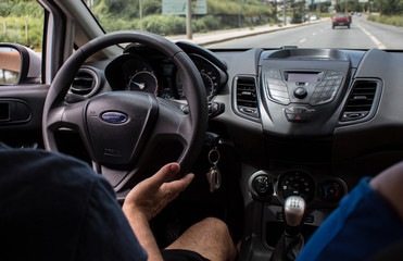 Selective focus man's hand on steering wheel, driving a car at sunset. Travel background