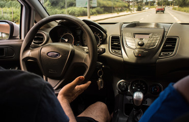 Selective focus man's hand on steering wheel, driving a car at sunset. Travel background
