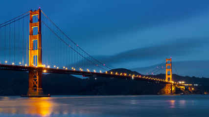 Nighttime view of Golden Gate Bridge on a dark blue sky background; California