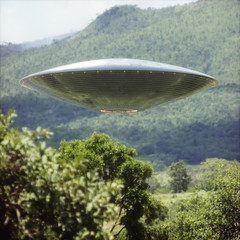 Unidentified Flying Object UFO. Unidentified flying object over a forest with trees and mountains behind. © ktsdesign
