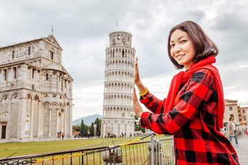 Young woman traveler making funny poses in front of the famous leaning tower in Pisa, Italy. Happy...