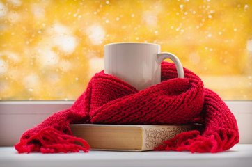 Autumn still life - Warm knitted scarf and cup of tea near a window, copy space.