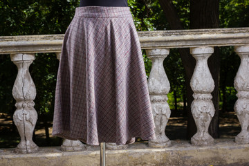 Plaid skirt on mannequin. Skirt straight cut on background of green trees. Women's skirt with natural fabric sewn to order. Tailoring