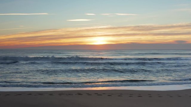 Flying over the beach and ocean during a sunrise 