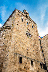 Side facade of the Cathedral Basilica of Santa Maria Annunziata, with the rose window and the apse, in Piazza Innocenzo III. Stone buildings from the Middle Ages. Anagni, Frosinone, Italy.