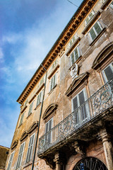 An ancient palace ruined by time, in the center of Anagni, Frosinone, Italy. Balcony with iron railing, windows with marble frames and decorations and wooden shutters.