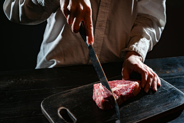 chef prepares rib-eye steak from a piece of fresh marbled beef