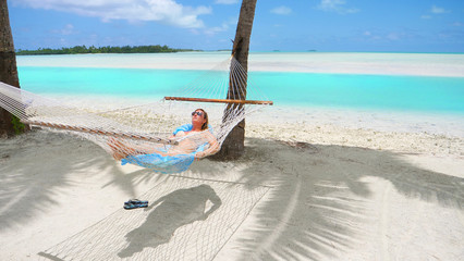 Fototapeta na wymiar CLOSE UP: Cheerful young woman relaxing under the palms in a comfortable hammock