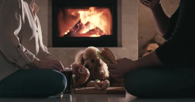 Young couple have romantic dinner with hot dogs and beer over fireplace background. Romantic concept.