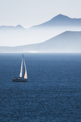 Fototapeta premium sea with sailboat and mountains of an islan