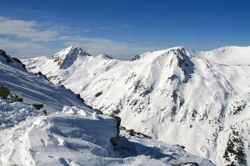 Fototapeta na wymiar Winter landscape with hills covered with snow at Pirin Mountain, view from Todorka peak, Bulgaria
