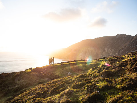 Gruppe junger Menschen an den Klippen von Slieve League in Irland Donnegal bei Sonnenuntergang