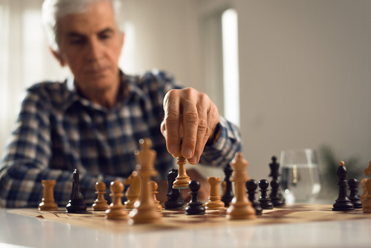 Close up of senior man playing chess at home