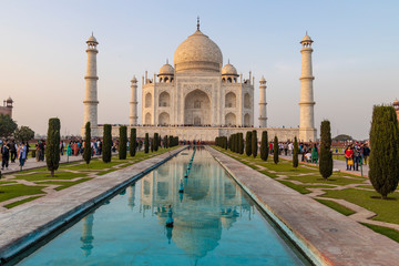 Taj Mahal Agra with Mughal architecture gateway at sunset with water reflection.