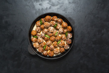 Juicy diet meatballs in a frying pan on a black table.