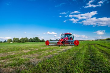 Czerwony traktor podczas zbioru siana. Baloty. Lato - obrazy, fototapety, plakaty