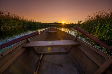 Drewniana łódź z wiosłami na jeziorze i bagnach. Wschód i zachód słońca. Biebrza, Polska