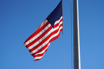 Fototapeta premium waving USA flag on pole against blue sky