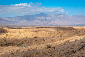Rugged desert landscape in Anza Borrego State Desert Park with mountains in clouds in the background.