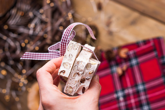 Traditional Italian sweet from nougat and almond for Christmas. Candy in a female hand. Free space for text.
