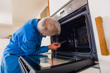 Mature workman fixing oven