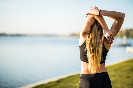 Rear view of fit girl stratching in park