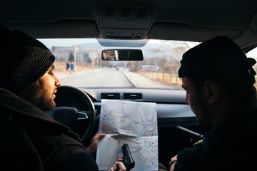 Criminals sitting at sunset in a car, looking at the city map and planning their next move.