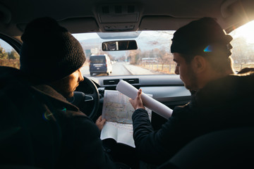 Two violent robbers sitting in a car looking at a blueprint of the building they want to rob while...