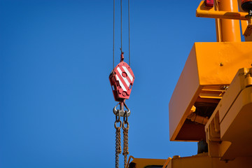 Crane hook with red and white stripes hanging, blue sky in background