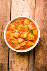 Indian food - Aloo curry masala. Potato cooked with spices and herbs in a tomato curry. served in a bowl over moody background. selective focus