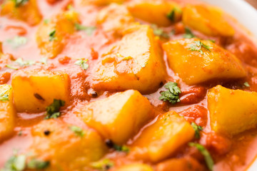 Indian food - Aloo curry masala. Potato cooked with spices and herbs in a tomato curry. served in a bowl over moody background. selective focus