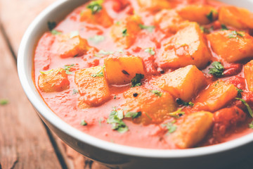 Indian food - Aloo curry masala. Potato cooked with spices and herbs in a tomato curry. served in a bowl over moody background. selective focus