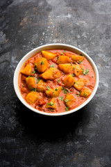 Indian food - Aloo curry masala. Potato cooked with spices and herbs in a tomato curry. served in a bowl over moody background. selective focus