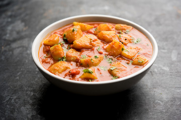 Indian food - Aloo curry masala. Potato cooked with spices and herbs in a tomato curry. served in a bowl over moody background. selective focus