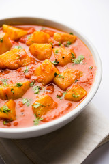 Indian food - Aloo curry masala. Potato cooked with spices and herbs in a tomato curry. served in a bowl over moody background. selective focus