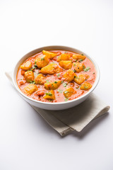 Indian food - Aloo curry masala. Potato cooked with spices and herbs in a tomato curry. served in a bowl over moody background. selective focus