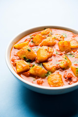 Indian food - Aloo curry masala. Potato cooked with spices and herbs in a tomato curry. served in a bowl over moody background. selective focus
