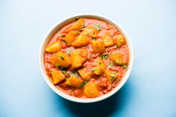 Indian food - Aloo curry masala. Potato cooked with spices and herbs in a tomato curry. served in a bowl over moody background. selective focus
