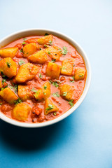 Indian food - Aloo curry masala. Potato cooked with spices and herbs in a tomato curry. served in a bowl over moody background. selective focus