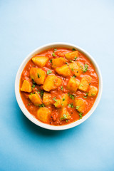 Indian food - Aloo curry masala. Potato cooked with spices and herbs in a tomato curry. served in a bowl over moody background. selective focus