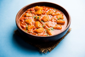 Indian food - Aloo curry masala. Potato cooked with spices and herbs in a tomato curry. served in a bowl over moody background. selective focus