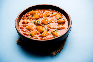 Indian food - Aloo curry masala. Potato cooked with spices and herbs in a tomato curry. served in a bowl over moody background. selective focus