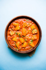 Indian food - Aloo curry masala. Potato cooked with spices and herbs in a tomato curry. served in a bowl over moody background. selective focus