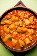Indian food - Aloo curry masala. Potato cooked with spices and herbs in a tomato curry. served in a bowl over moody background. selective focus