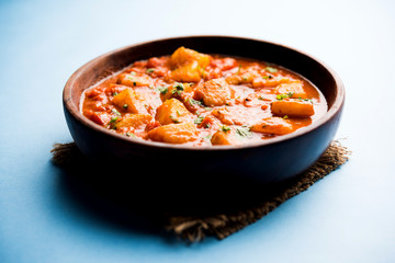 Indian food - Aloo curry masala. Potato cooked with spices and herbs in a tomato curry. served in a bowl over moody background. selective focus